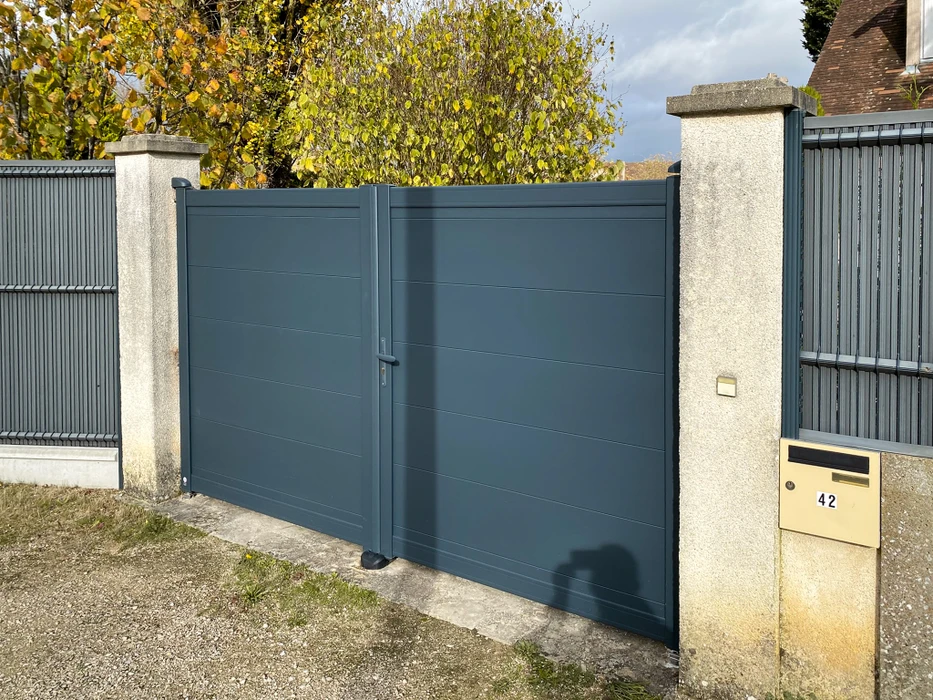 Portail double battant en aluminium laqué gris anthracite, à lames horizontales pleines, monté entre deux piliers en béton
