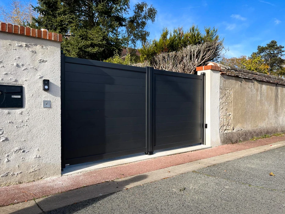 Portail double vantaux en aluminium laqué anthracite (RAL 7016), à lames horizontales pleines, motorisé, installé entre deux piliers maçonnés enduits