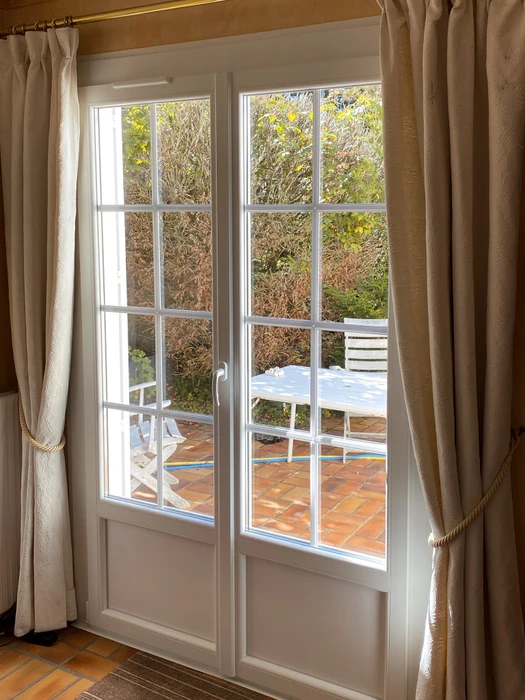 Porte-fenêtre double vantail blanche avec petits-bois, vue depuis l'intérieur