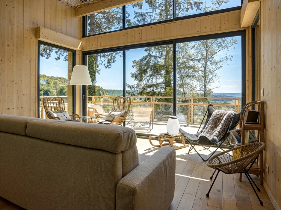 Salon moderne avec grandes baies vitrées panoramiques offrant vue sur paysage verdoyant