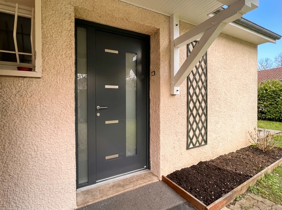 Façade extérieure d'une maison, porte-fenêtre coulissante blanche à petits bois, double vantail vitré avec imposte fixe