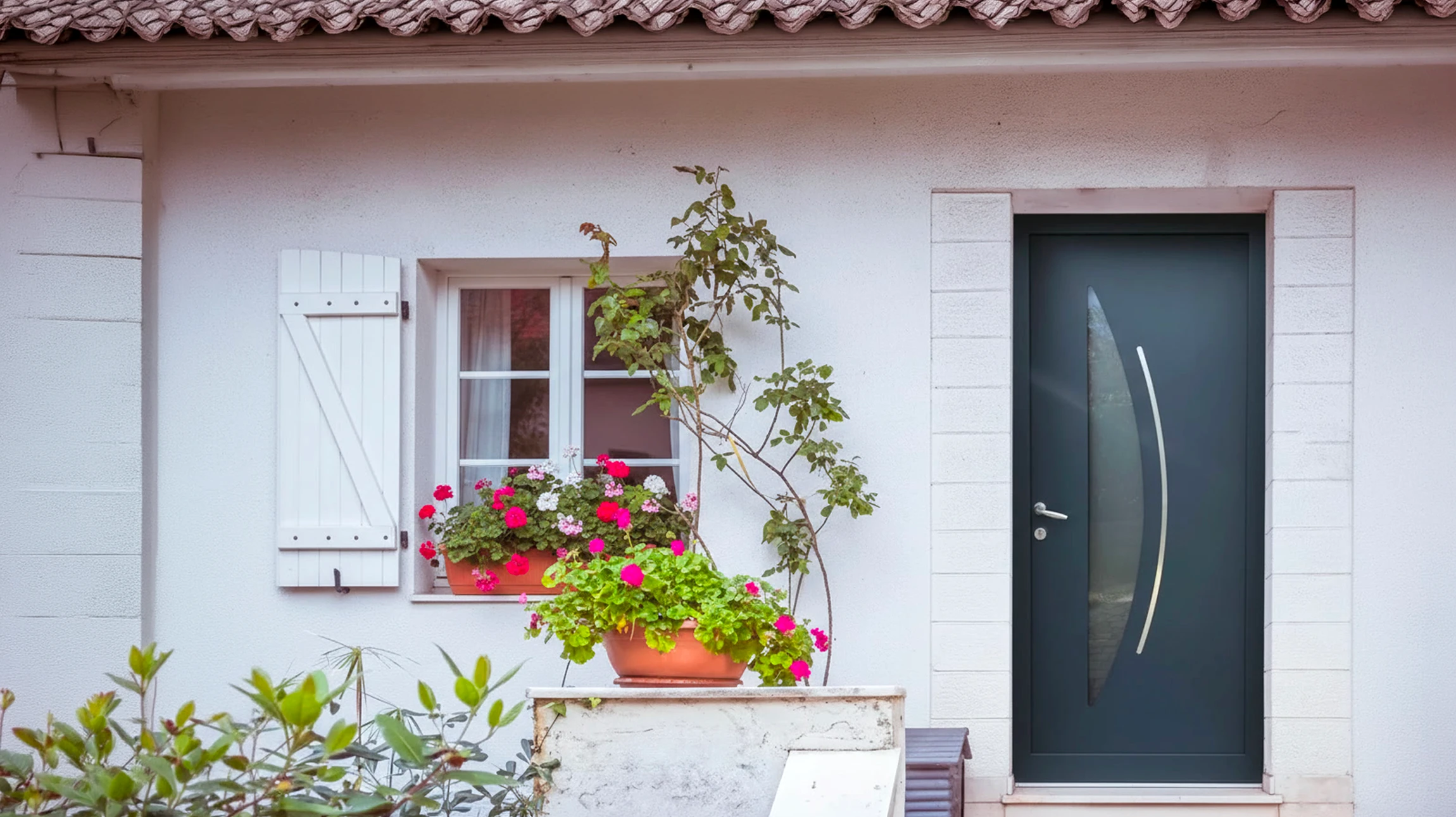 Façade méditerranéenne avec porte d'entrée bleue à imposte vitré décoratif, mur crépi blanc encadré de pierre naturelle