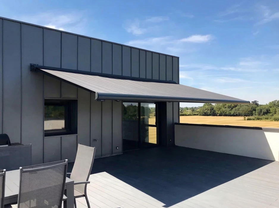 Terrasse extérieure avec pergola bioclimatique à lames orientables en aluminium anthracite, fixée en applique sur façade enduit blanc