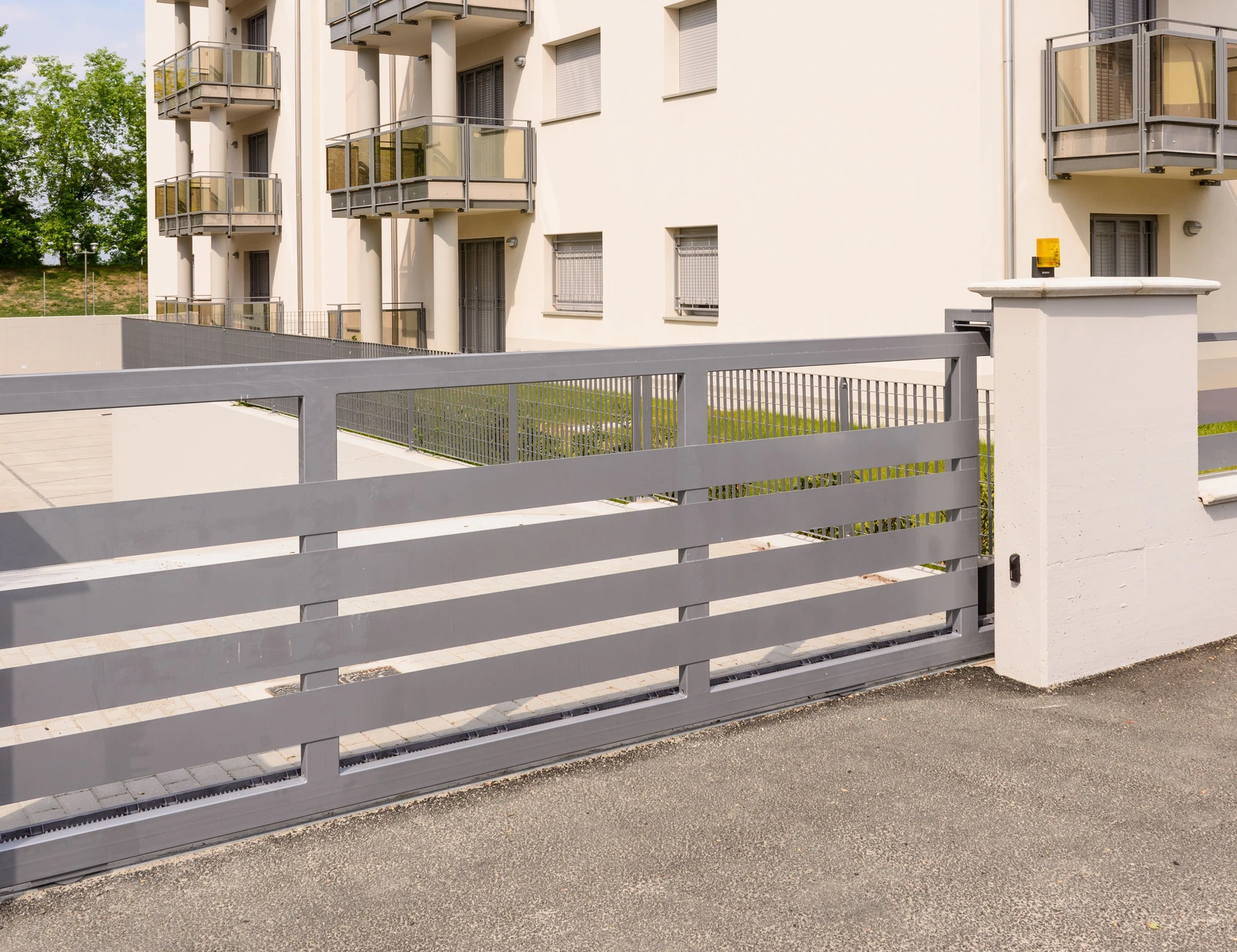 Portail coulissant métallique gris installé devant une résidence moderne avec façade en briques beiges
