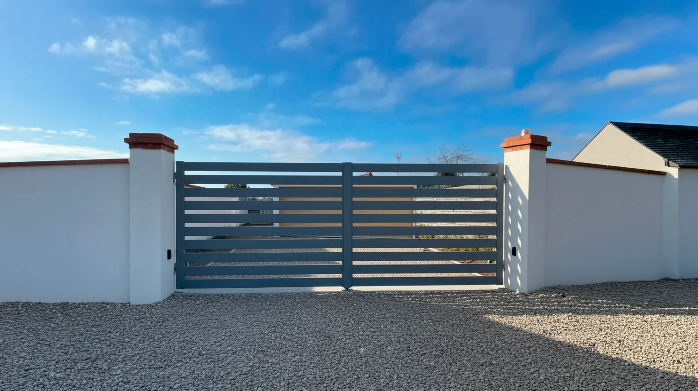 Scène extérieure d'un complexe résidentiel moderne avec portail coulissant automatique en aluminium gris