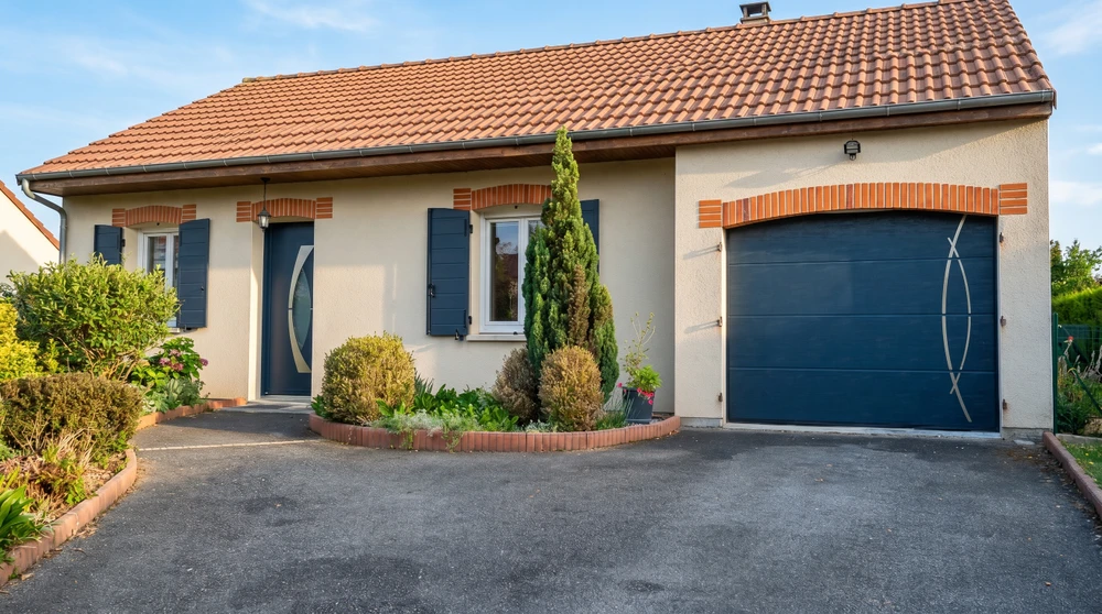 Extérieur résidentiel moderne avec porte de garage sectionnelle anthracite à panneaux horizontaux lisses, intégrée dans façade blanche contemporaine